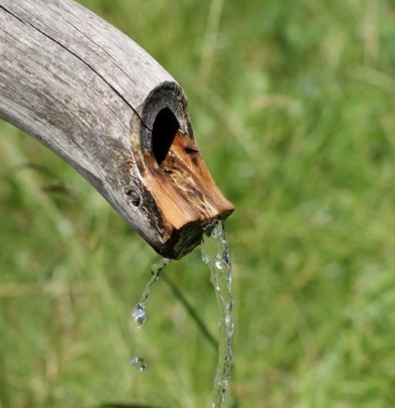 Wasser läuft aus einen Holzbrunnen