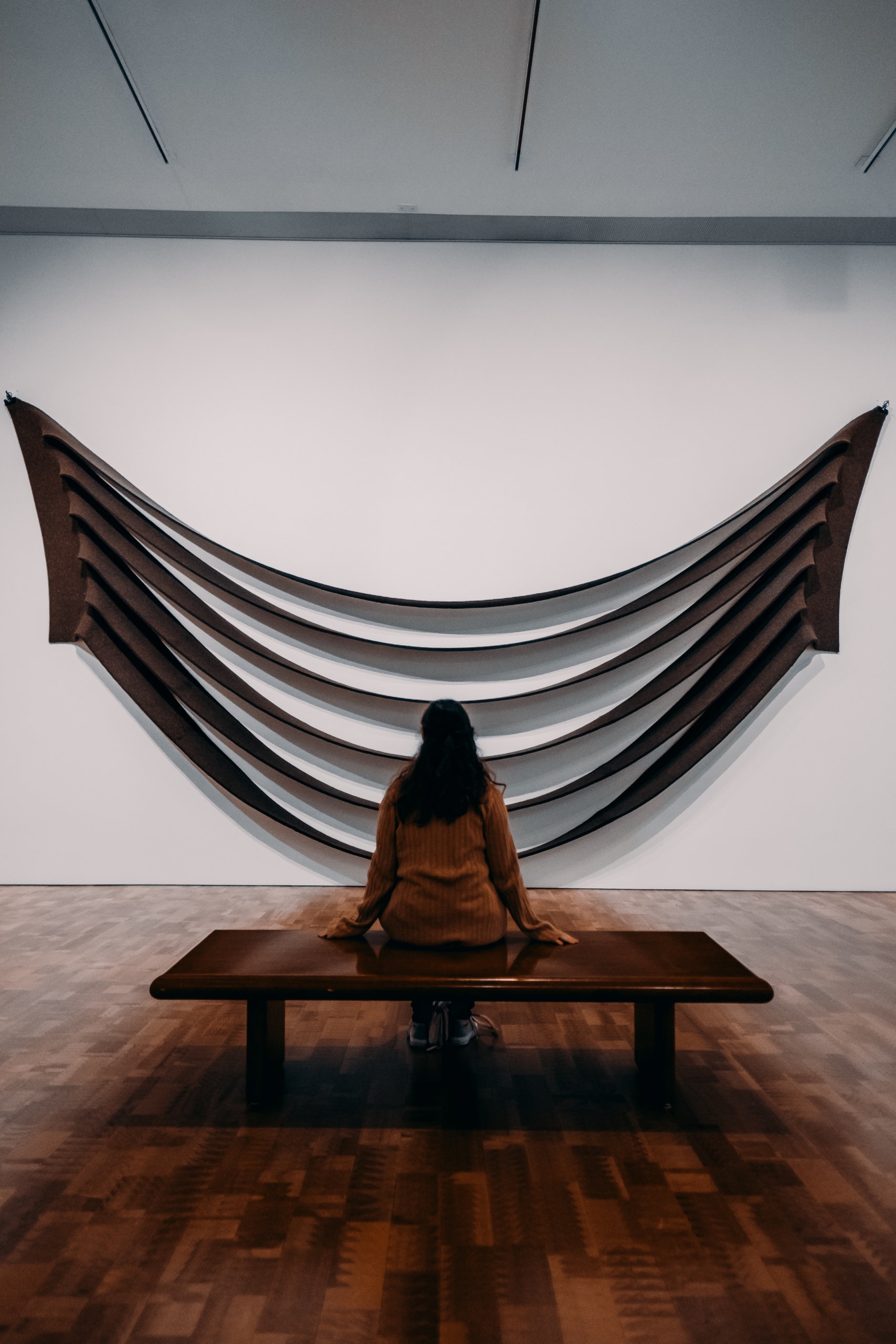 Eine Frau sitzt vor einem hölzernen Ausstellungsstück in einem Museum