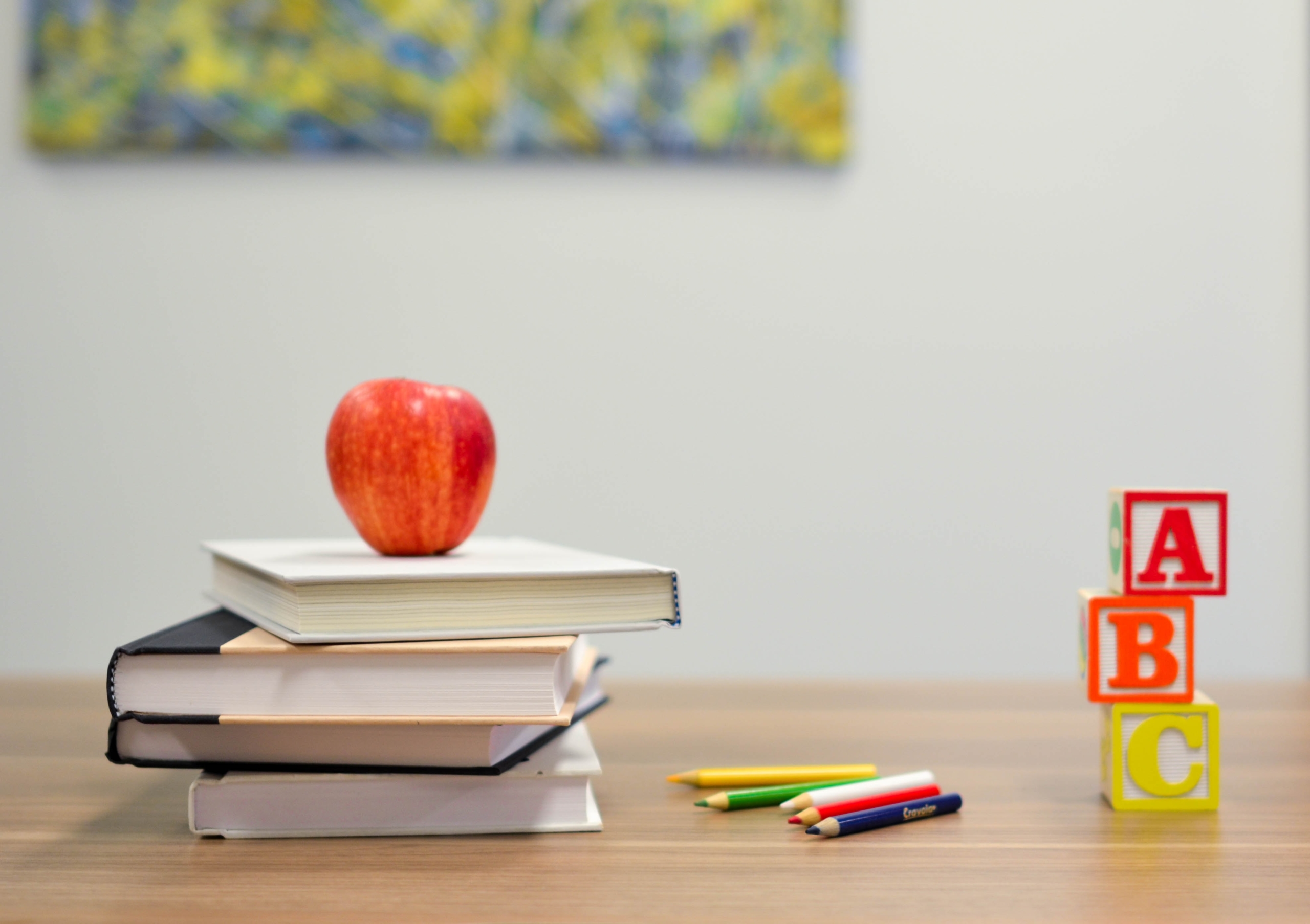 Ein Apfel auf einem Stabel Bücher, nebenbei Spielzeug und ein paar Stifte