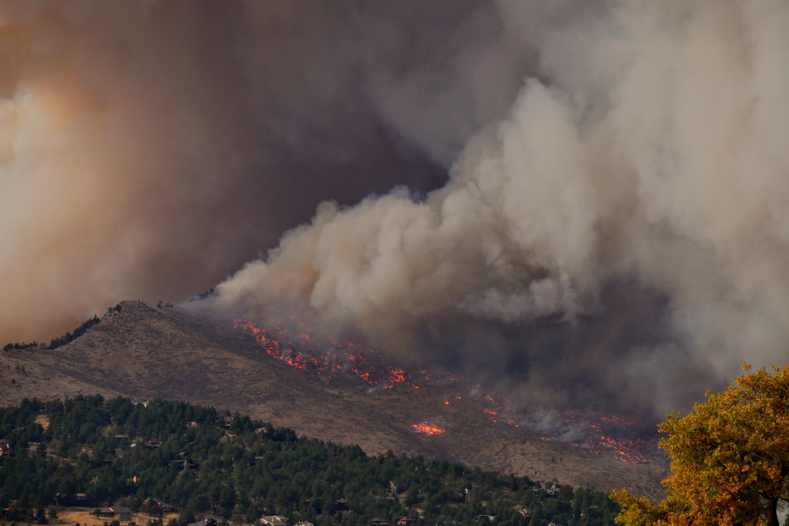 Ein großer Waldbrand brennt auf einem bewaldeten Hügel und hüllt die Umgebung in Rauch 