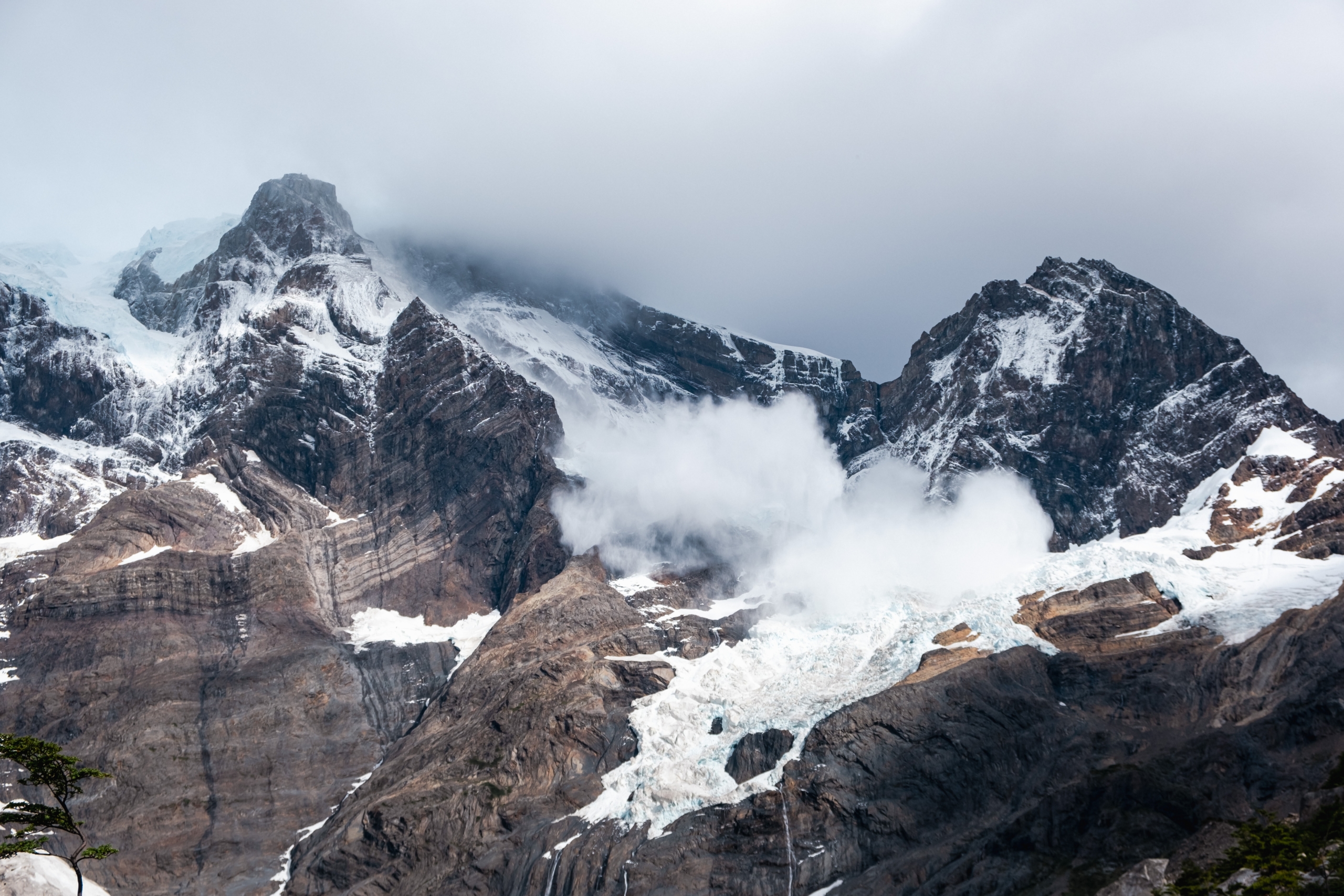 Blick auf einen teilweise in Wolken eingehüllten, verschneiten Felshang 