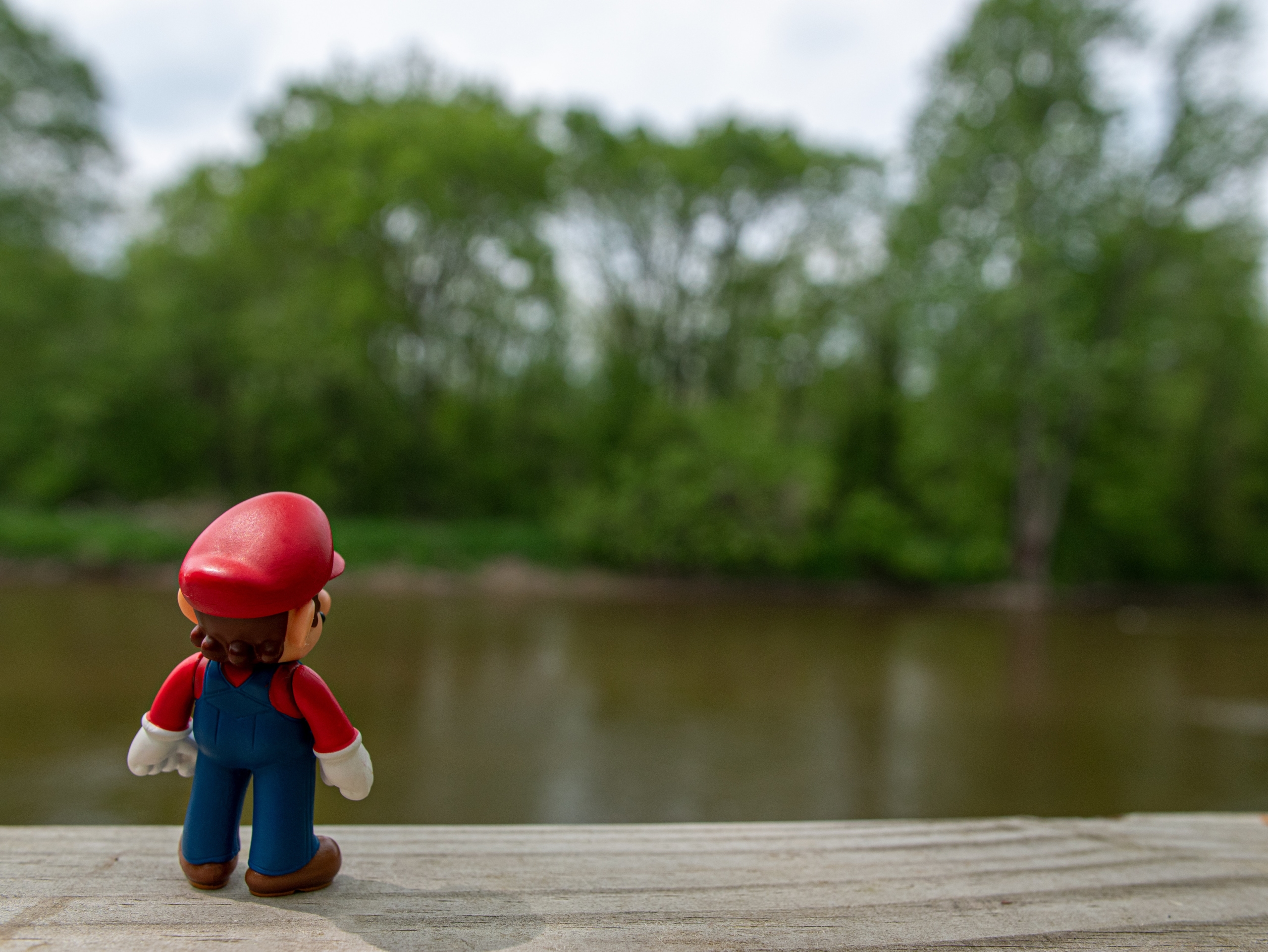 Eine Spielfigur steht vor einem Teich in einem Park / Nahaufnahme