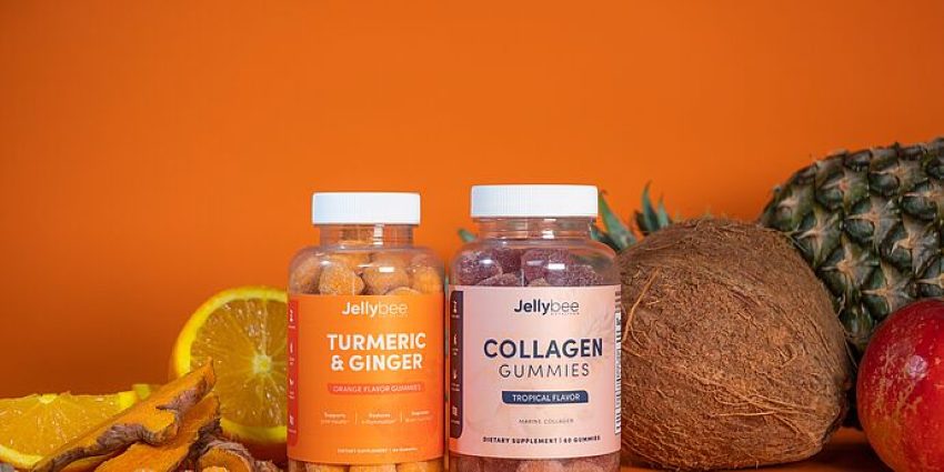 Zwei Dosen mit Nahrungsergänzungsmitteln in Form von Vitaminkapseln und verschiedenes Obst auf einem Tisch