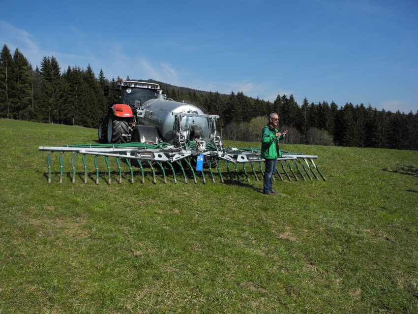 Traktor beim Gülle ausbringen und ein Mensch davor
