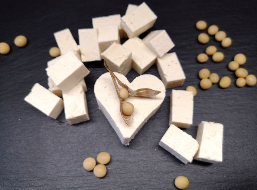 Tofu natur - aufgeschnitten und als Herzform ausgestochen, schön angerichtet auf schwarzer Schieferplatte