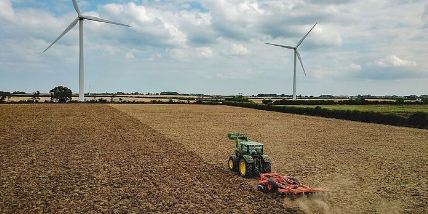 A tractor with a tillage implement is cultivating a field