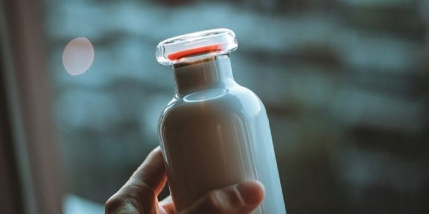 eine Glasflasche mit Milch gefüllt, die von jemandem gehalten wird