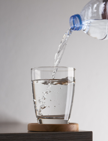 Wasser aus einer Flasche wird in ein Glas eingeschenkt